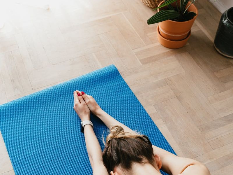 A well-lit, serene room prepared for a yoga practice, with a mat on the floor.